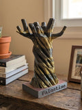 Decorative sculpture of twisted branches on a small platform with 'Palestine' written on it, placed on a wooden surface.