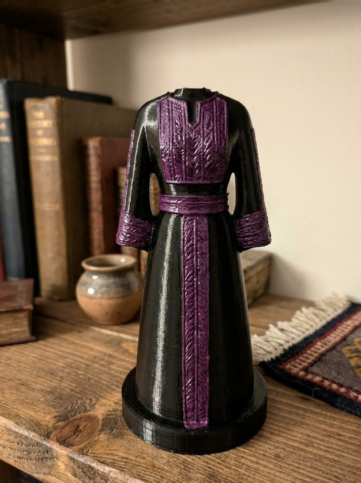 Black and purple dress form on a wooden shelf with books and decor.
