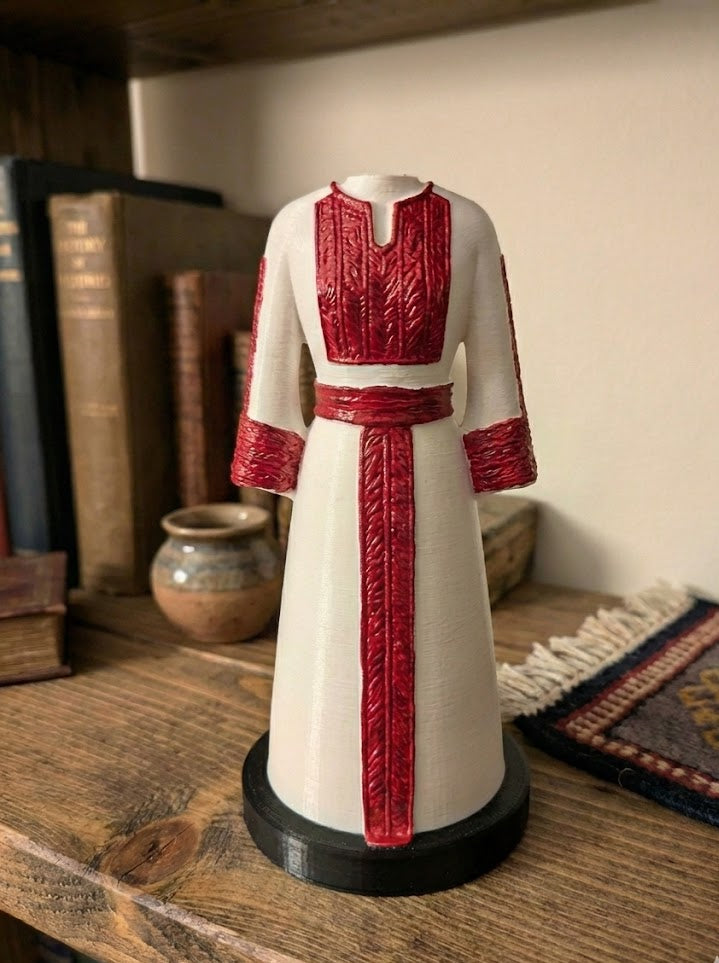 Mannequin wearing a white dress with red accents on a wooden surface.